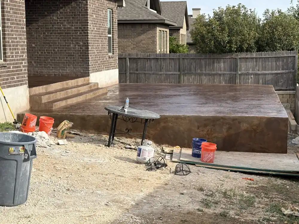 Stained concrete patio, reddish-brown, steps beside brick house, San Antonio